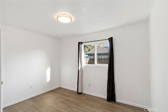 spare room with wood finished floors and baseboards