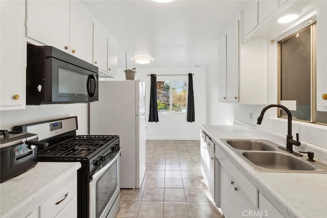 kitchen with black microwave, gas range, light countertops, white cabinetry, and a sink