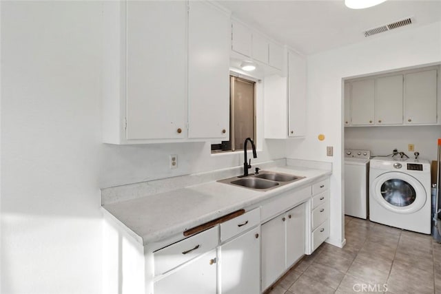 washroom with visible vents, a sink, cabinet space, separate washer and dryer, and light tile patterned flooring