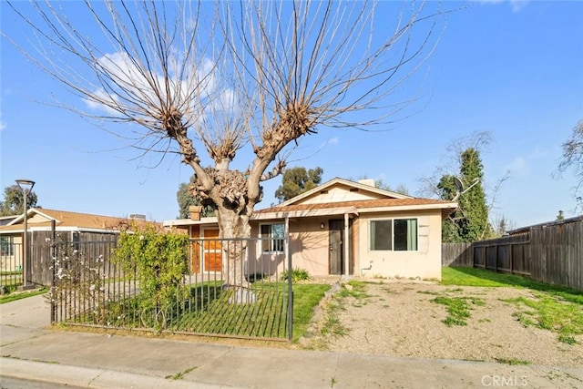 bungalow-style home with a fenced front yard and stucco siding