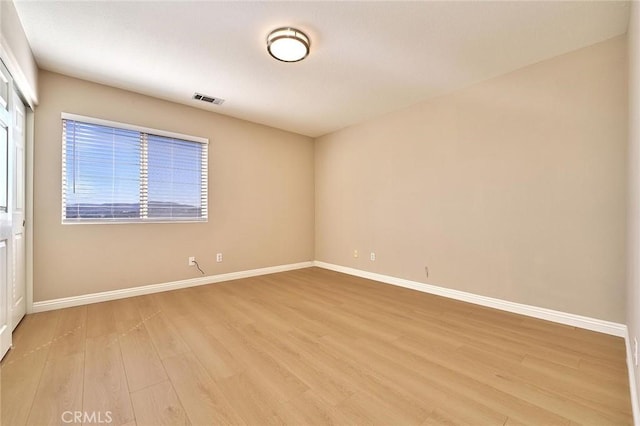 spare room featuring visible vents, light wood-style flooring, and baseboards