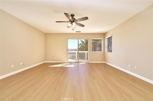 empty room featuring visible vents, a ceiling fan, light wood-type flooring, and baseboards