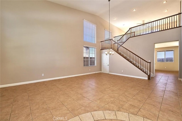 unfurnished living room with high vaulted ceiling, stairway, an inviting chandelier, light tile patterned flooring, and baseboards