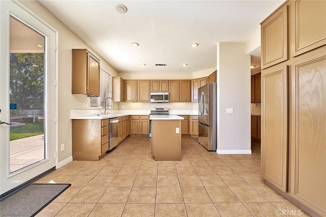 kitchen featuring a center island, light countertops, appliances with stainless steel finishes, light tile patterned flooring, and a sink