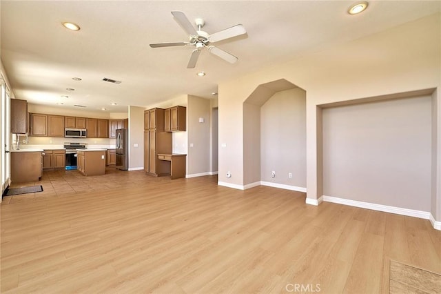 unfurnished living room with baseboards, visible vents, light wood finished floors, and ceiling fan