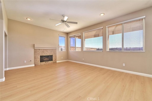 unfurnished living room featuring recessed lighting, light wood-style floors, a fireplace, baseboards, and ceiling fan