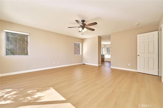 spare room with baseboards, light wood-type flooring, and ceiling fan