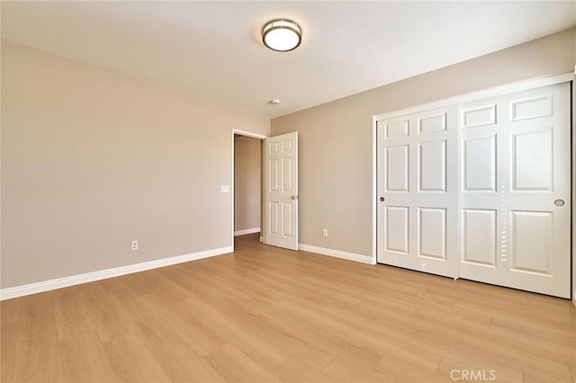 unfurnished bedroom featuring a closet, baseboards, and light wood-style floors