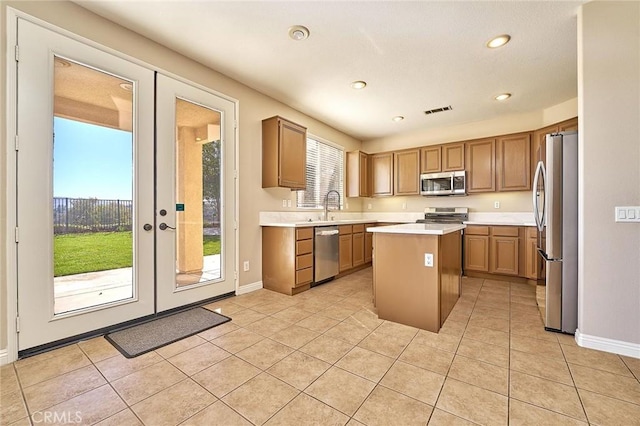 kitchen featuring light tile patterned floors, stainless steel appliances, a kitchen island, and light countertops