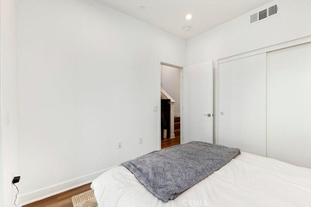 bedroom featuring visible vents, baseboards, recessed lighting, wood finished floors, and a closet