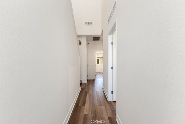 hallway with visible vents, baseboards, and wood finished floors