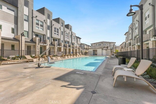 pool with a residential view, a patio, and fence