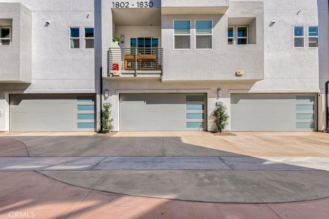 view of front of house with a balcony, stucco siding, and a garage