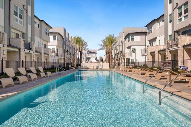 community pool featuring a residential view, a patio, and fence