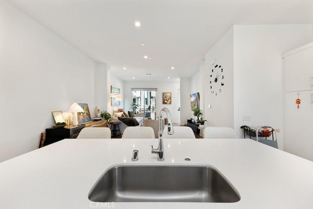 kitchen with open floor plan, recessed lighting, light countertops, and a sink