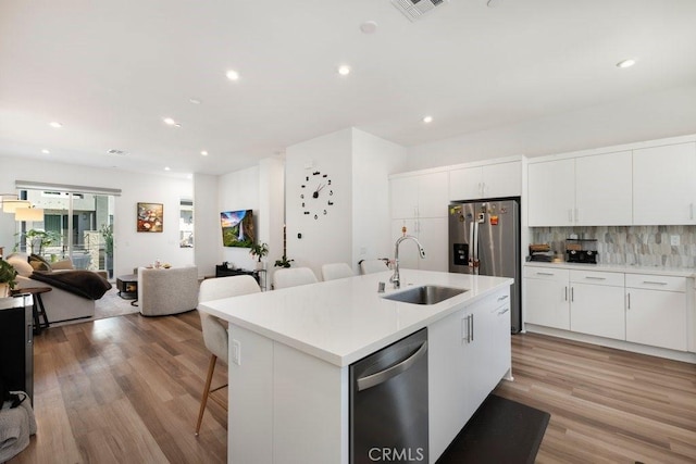 kitchen featuring a sink, decorative backsplash, appliances with stainless steel finishes, a kitchen bar, and open floor plan