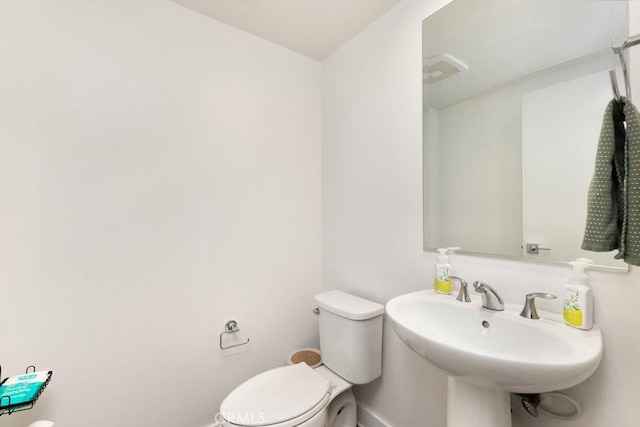 half bath featuring a sink, visible vents, and toilet