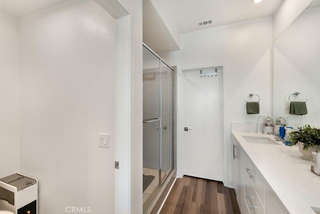 bathroom featuring vanity, visible vents, wood finished floors, and a stall shower