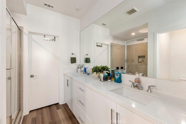 bathroom featuring a shower stall, wood finished floors, visible vents, and a sink