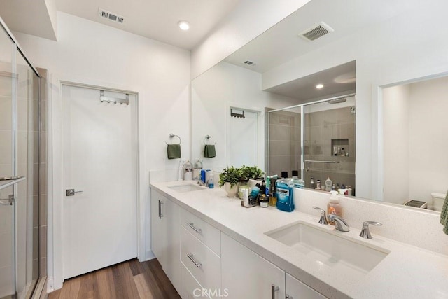 full bath featuring visible vents, a shower stall, wood finished floors, and a sink