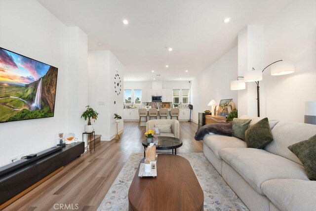 living room featuring recessed lighting, light wood-type flooring, and baseboards