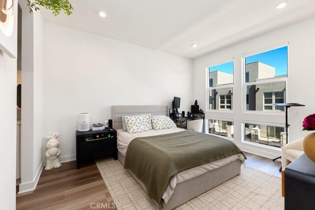 bedroom featuring light wood finished floors, recessed lighting, and baseboards