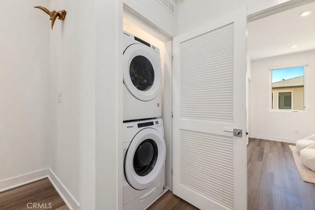 laundry room with stacked washer / dryer, recessed lighting, dark wood-type flooring, and baseboards