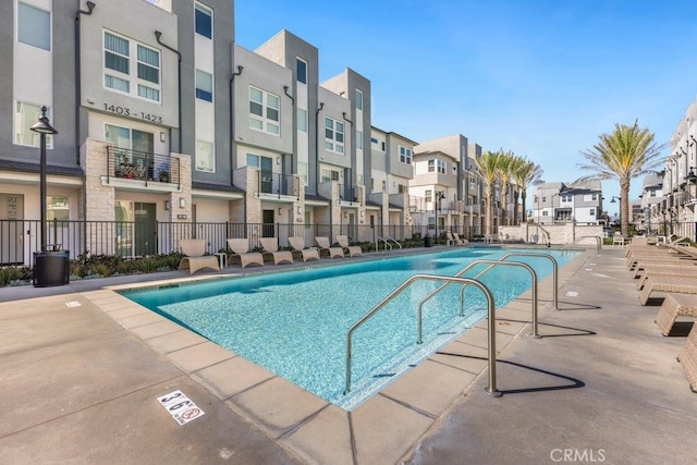 pool featuring a residential view, a patio, and fence