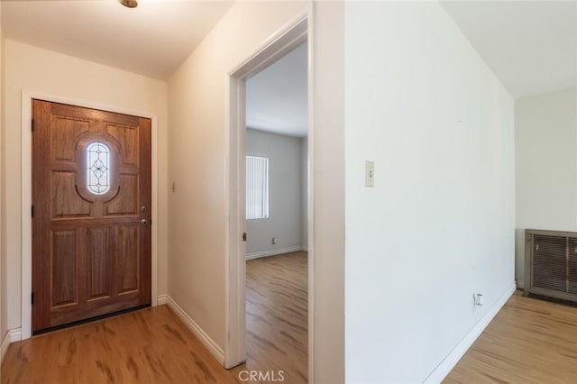 entrance foyer featuring a wealth of natural light, heating unit, baseboards, and light wood-style floors