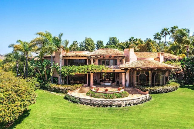 back of property with a yard, a patio, a chimney, and a tile roof