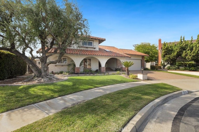 mediterranean / spanish home featuring stucco siding, driveway, a front yard, a garage, and a tiled roof