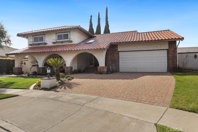 mediterranean / spanish-style home with stucco siding, a tiled roof, decorative driveway, and a garage