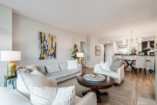 living room featuring a chandelier, baseboards, and light wood-style floors