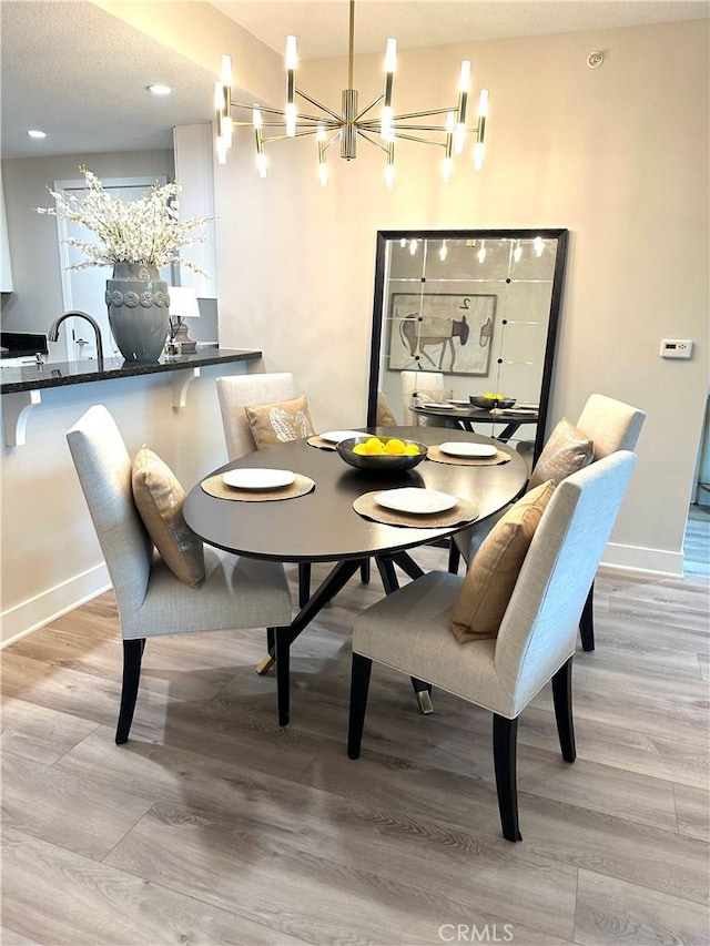 dining room featuring baseboards, an inviting chandelier, and light wood-style flooring