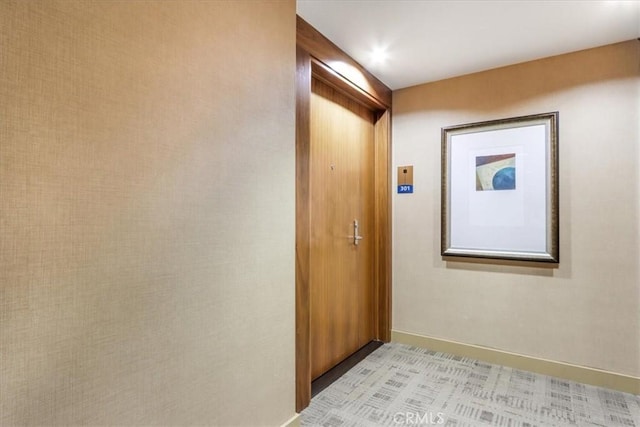 hall featuring light colored carpet and baseboards