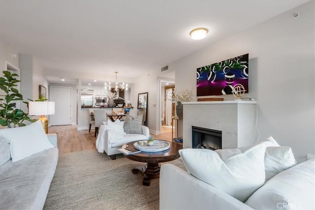 living area with a notable chandelier, a fireplace, visible vents, and baseboards