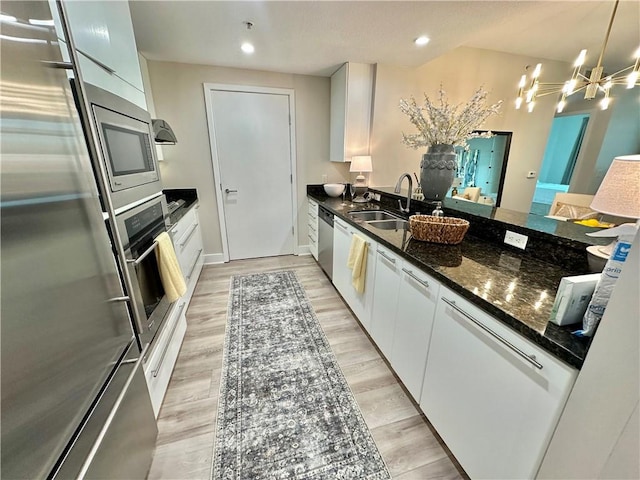 kitchen with a chandelier, white cabinetry, stainless steel appliances, and a sink