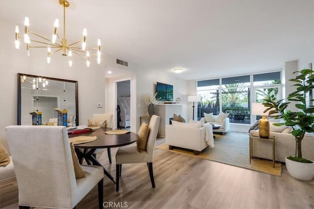 dining area with visible vents, floor to ceiling windows, an inviting chandelier, and wood finished floors