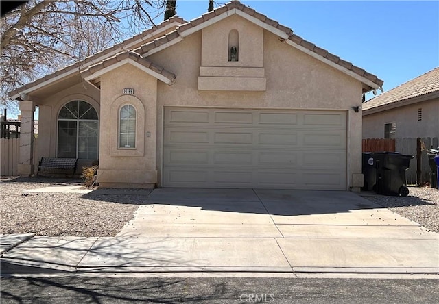 mediterranean / spanish-style home with fence, a tiled roof, stucco siding, a garage, and driveway