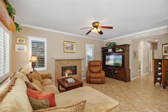 living area featuring light tile patterned flooring, a fireplace, a ceiling fan, and ornamental molding