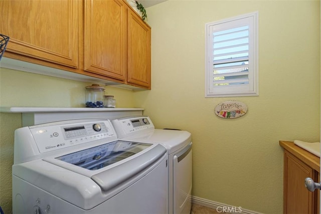 laundry room featuring washer and dryer, baseboards, and cabinet space