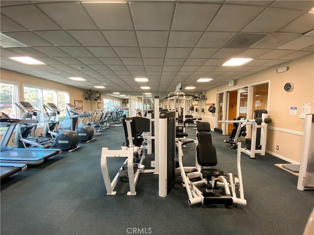 gym with a paneled ceiling and baseboards