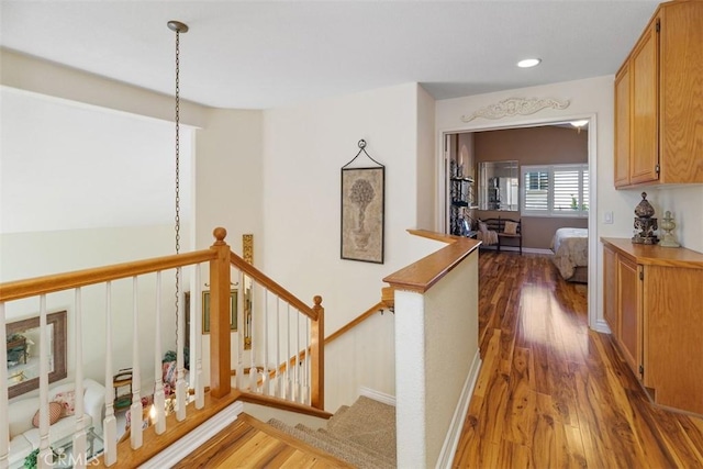 corridor with wood finished floors, an upstairs landing, and baseboards