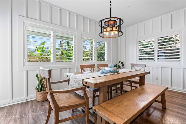 dining room with a decorative wall, an inviting chandelier, and wood finished floors