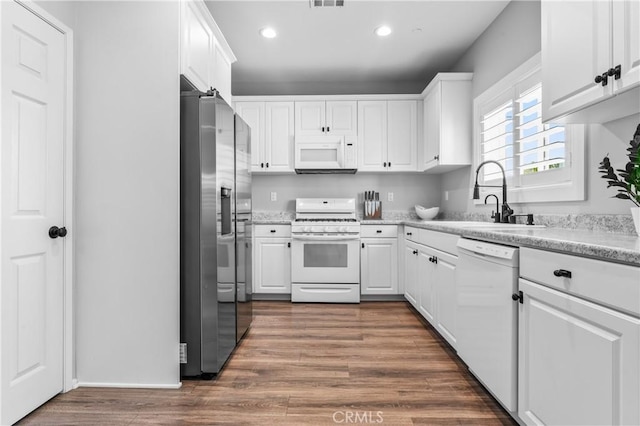 kitchen featuring a sink, dark wood-style floors, white appliances, and white cabinets