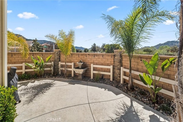 view of patio with a mountain view and fence