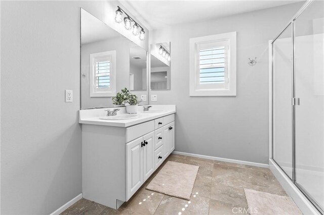 full bath with a sink, double vanity, baseboards, and a stall shower