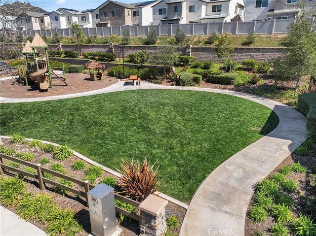 view of property's community featuring a residential view, a lawn, and fence