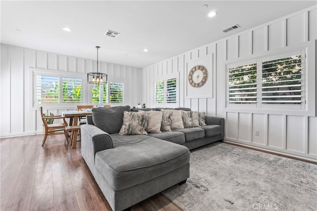 living room featuring a decorative wall, plenty of natural light, visible vents, and hardwood / wood-style flooring