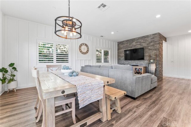 dining area with light wood finished floors, a decorative wall, a notable chandelier, and visible vents